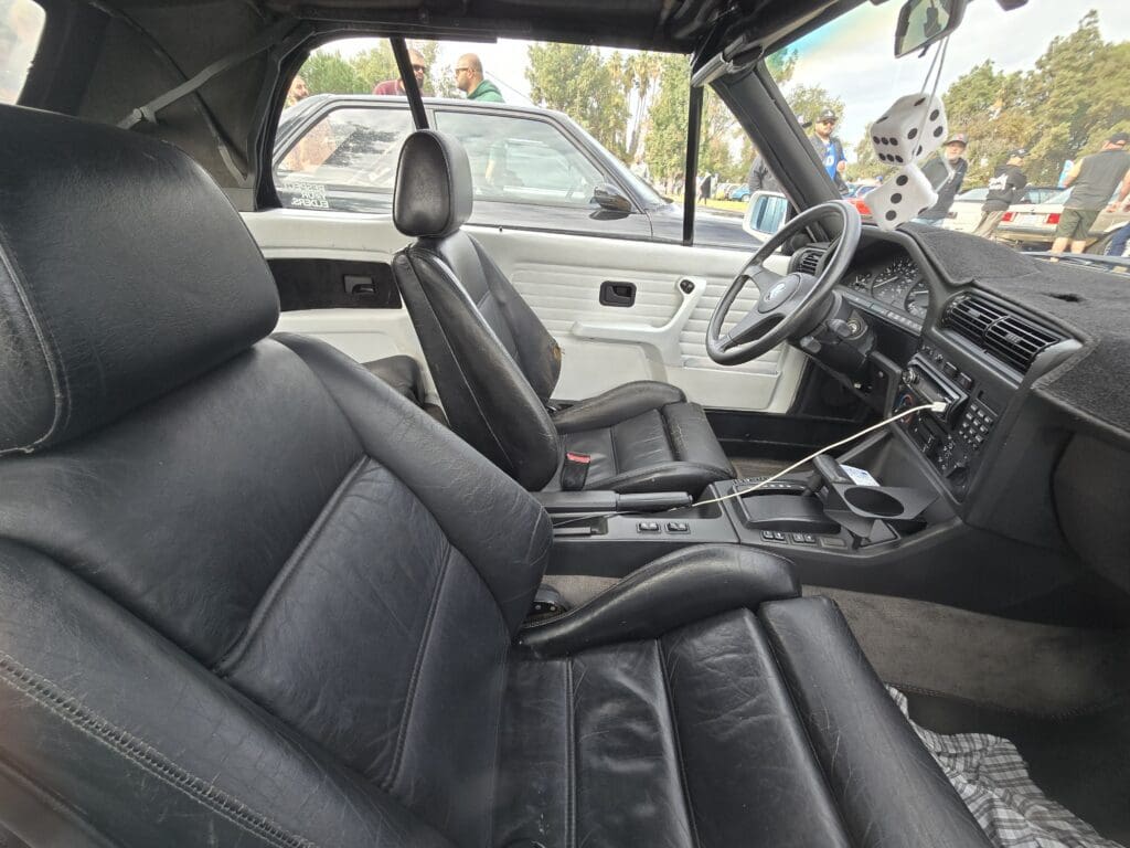Interior of a classic car featuring black leather seats and a manual transmission.