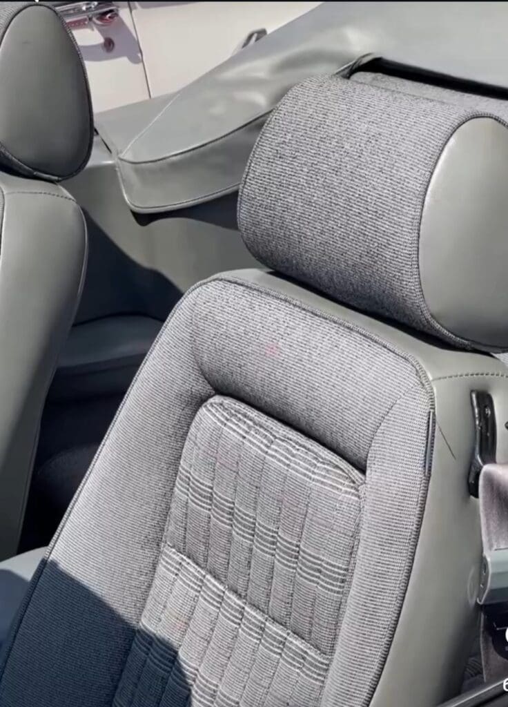 Close-up of a stylish gray car seat with detailed fabric and leather headrest.