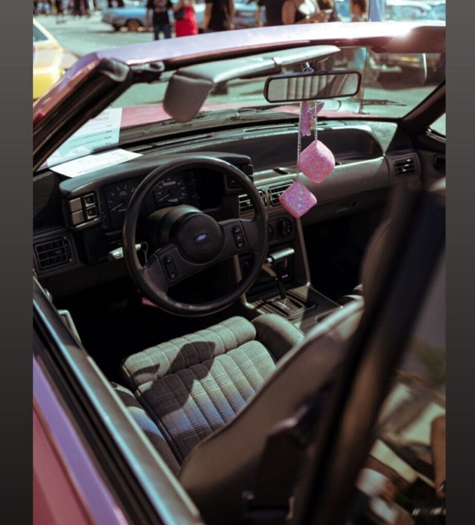 View of a car's interior with a steering wheel and decorative hanging items.
