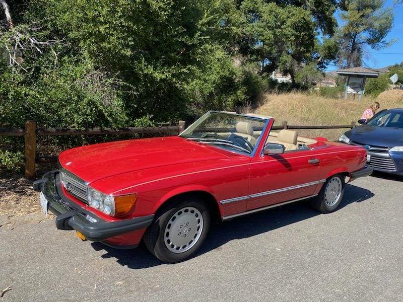 Classic red convertible car parked on a sunny day.