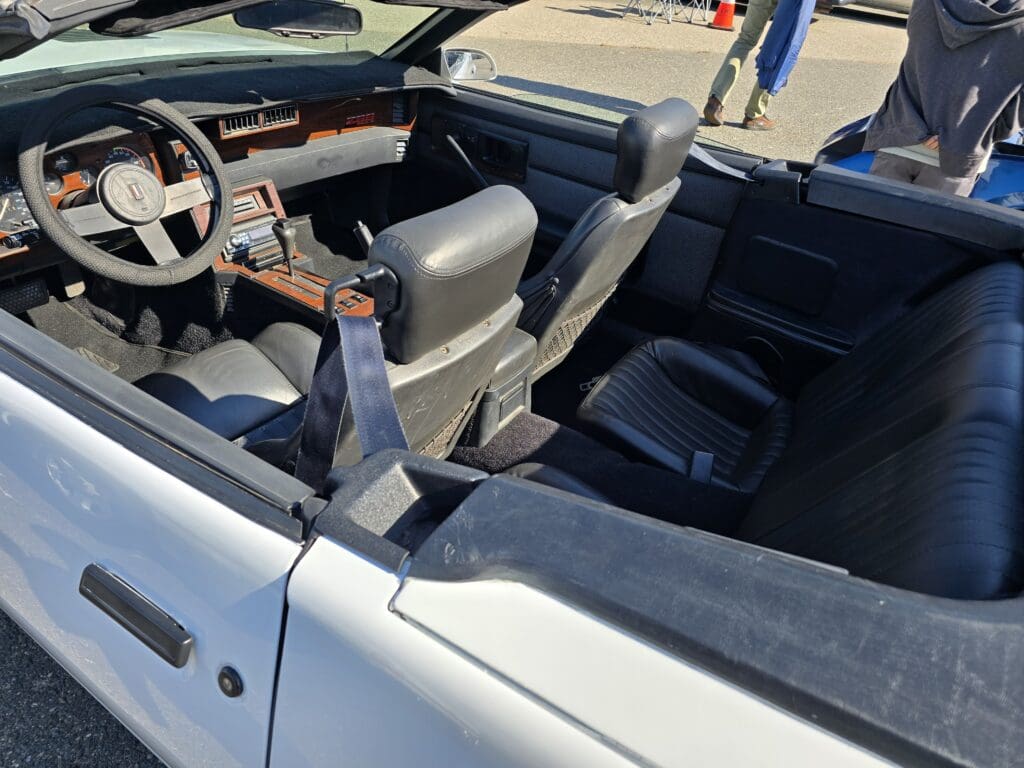 White convertible sports car parked on a sunny street.