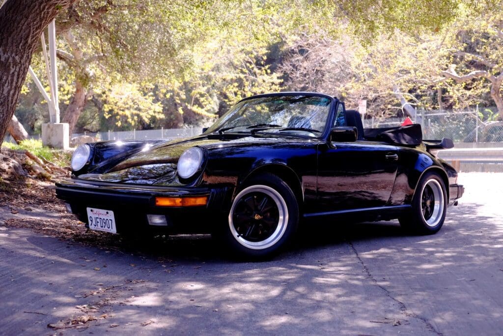 Classic black convertible sports car parked on a sunny day.