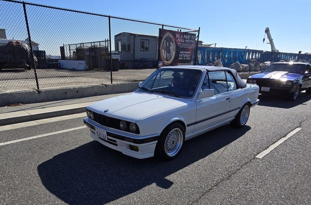 White BMW E30 parked outdoors on a sunny day.