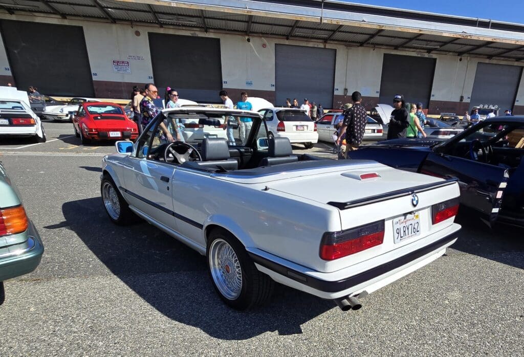 White BMW E30 parked outdoors on a sunny day.