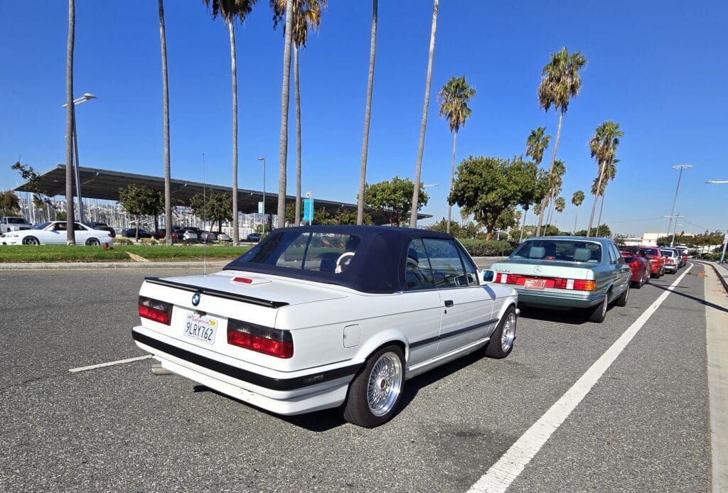 White BMW E30 parked outdoors on a sunny day.