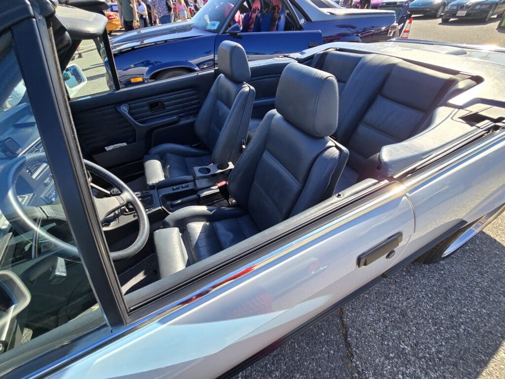 Silver convertible car with dark interior seats parked outdoors.