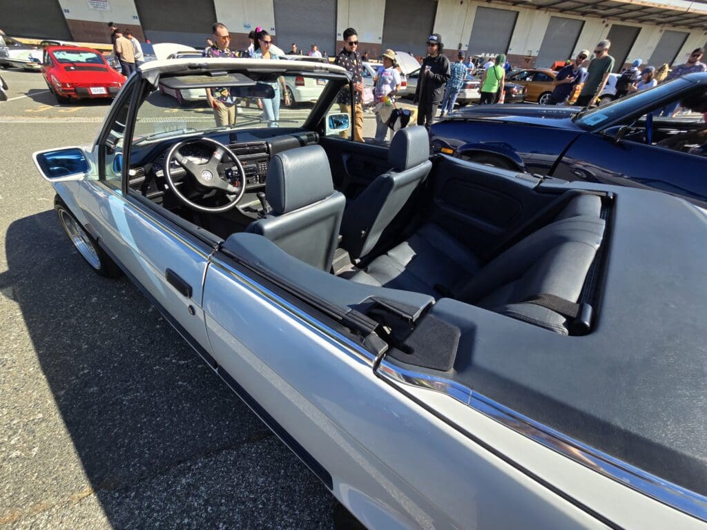 Classic silver convertible car with black interior at a car show.