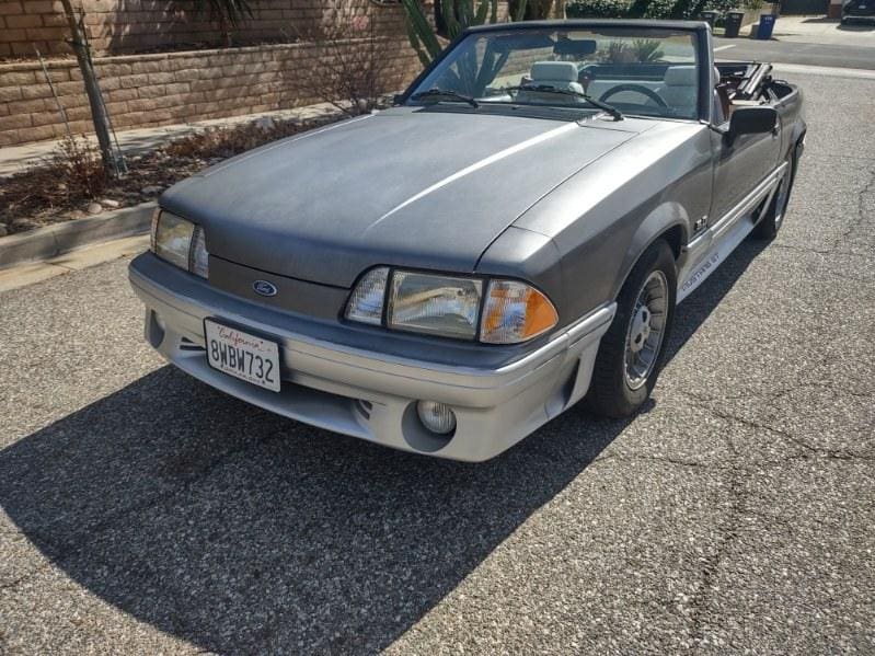 Silver convertible car parked on a sunny road.