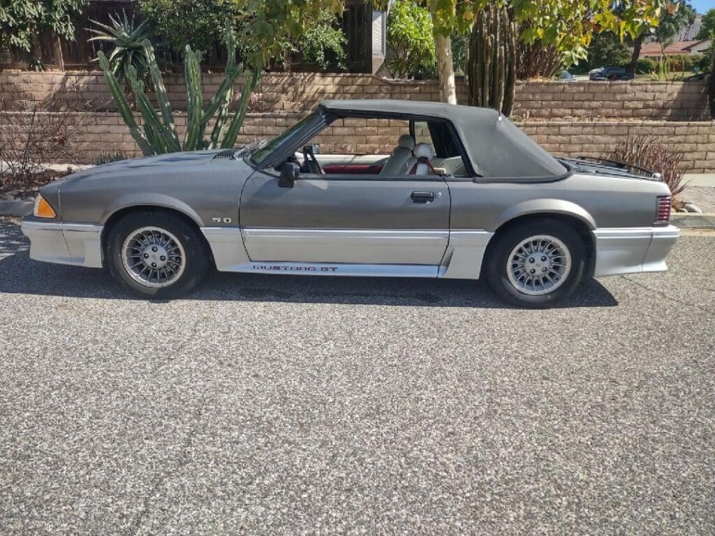 Silver convertible sports car parked on a sunny street.