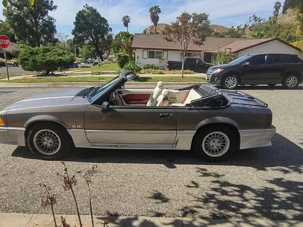 Classic silver convertible car parked on a sunny driveway.