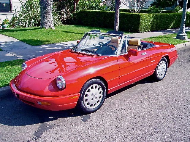 Red vintage convertible parked on a sunny street.