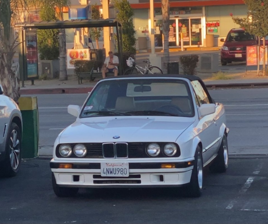 White convertible car parked outside a store in the evening.