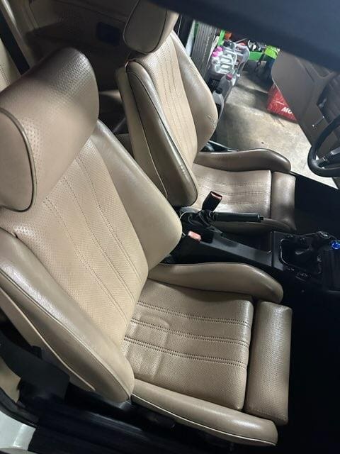 Interior view of beige leather car seats with a center console.