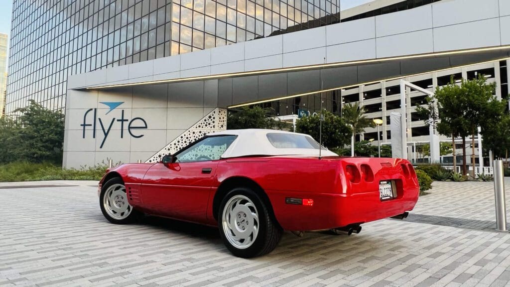 Red convertible sports car parked on a city street at sunset.