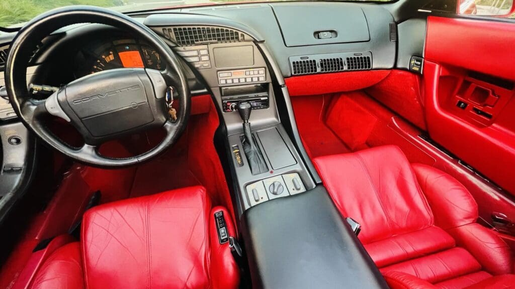 Interior of a vintage car with red leather seats and a classic dashboard.