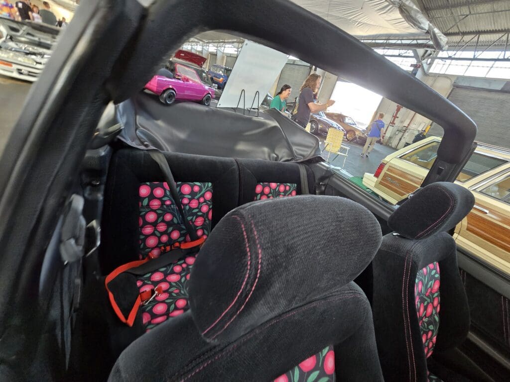 A pink convertible car parked in a sunny outdoor area.