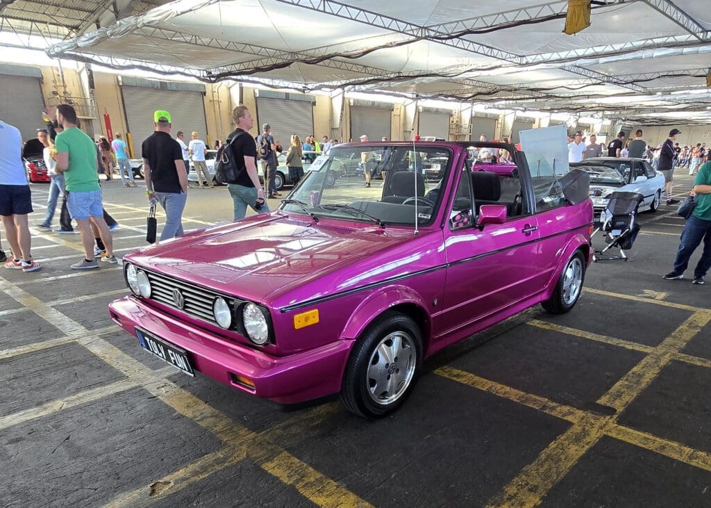 Bright pink vintage convertible car parked under a tent.
