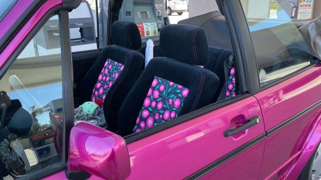 A vibrant pink car interior with colorful patterned seat cushions.