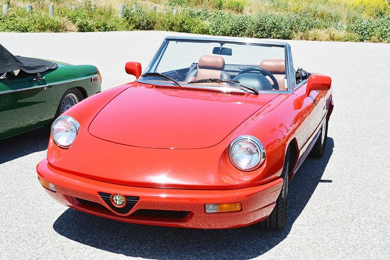 A red Alfa Romeo convertible sports car parked outdoors.