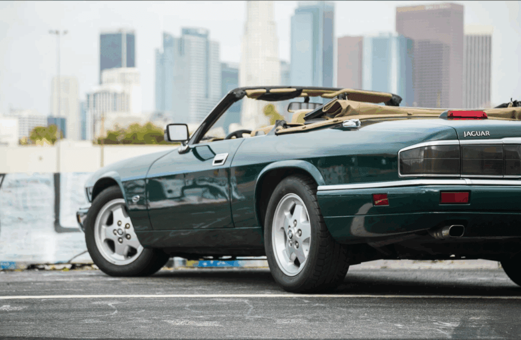 A classic green convertible sports car parked in an urban setting.