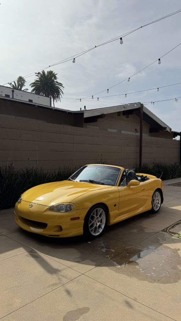 Yellow convertible sports car parked under a clear sky.