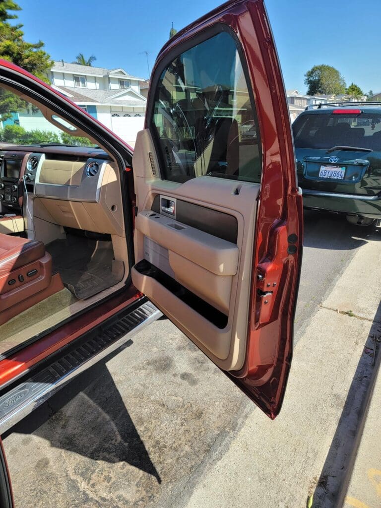 Open car door showing interior door panel and dashboard details.