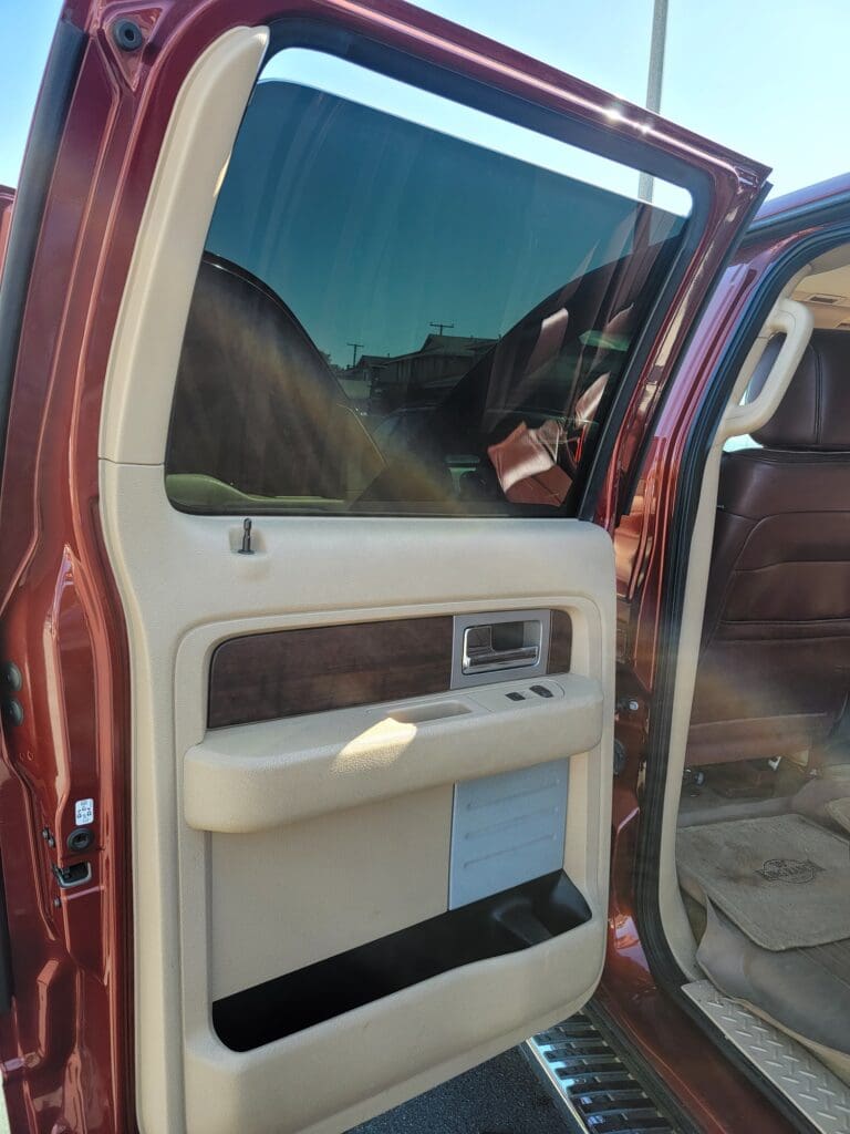 A close-up of a car door interior with a window and handle.