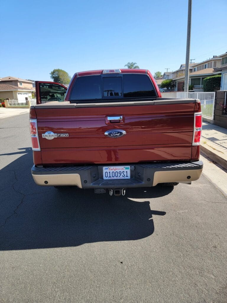 Rear view of a red Ford F-150 pickup truck parked on a street.