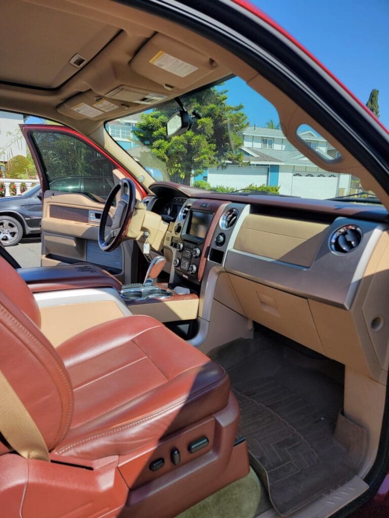 View of a car's interior with tan leather seats and open door.