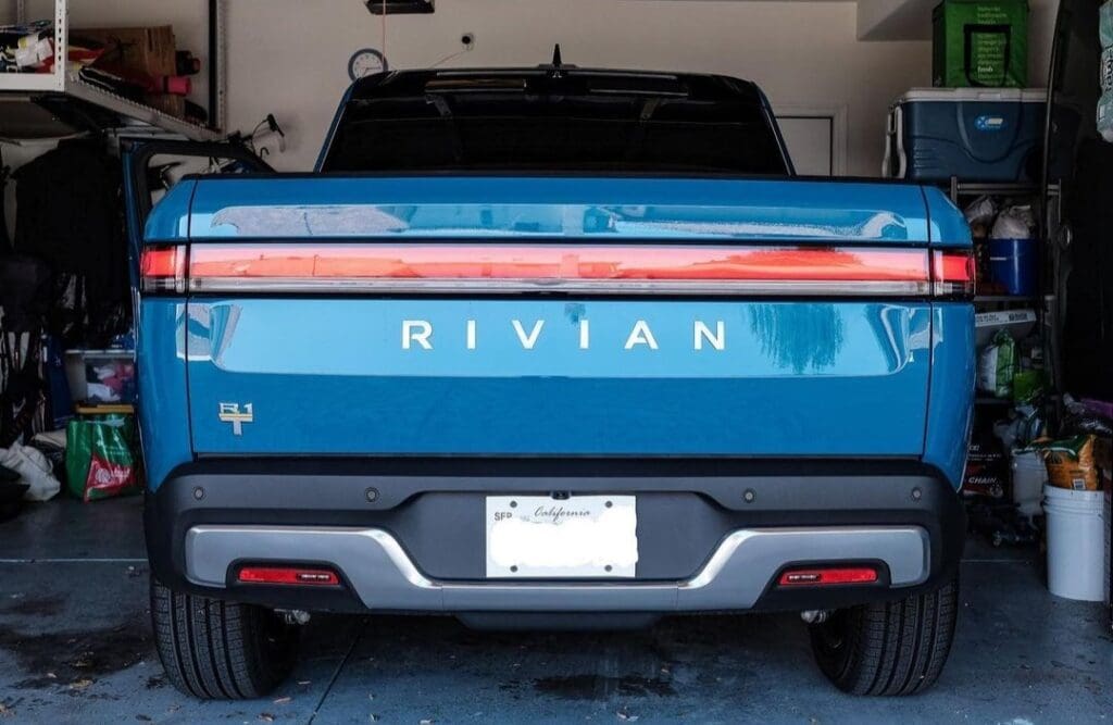Rear view of a blue Rivian electric truck parked in a garage.