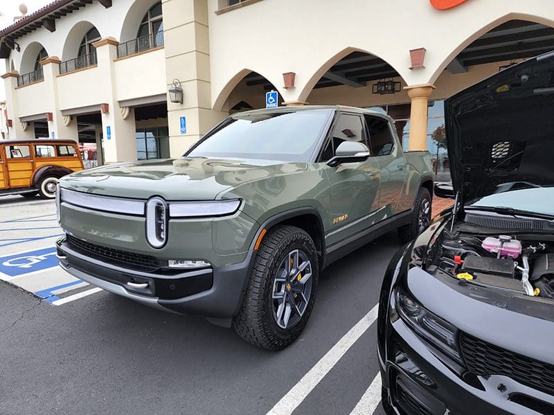 A green Rivian electric SUV parked with its hood open.