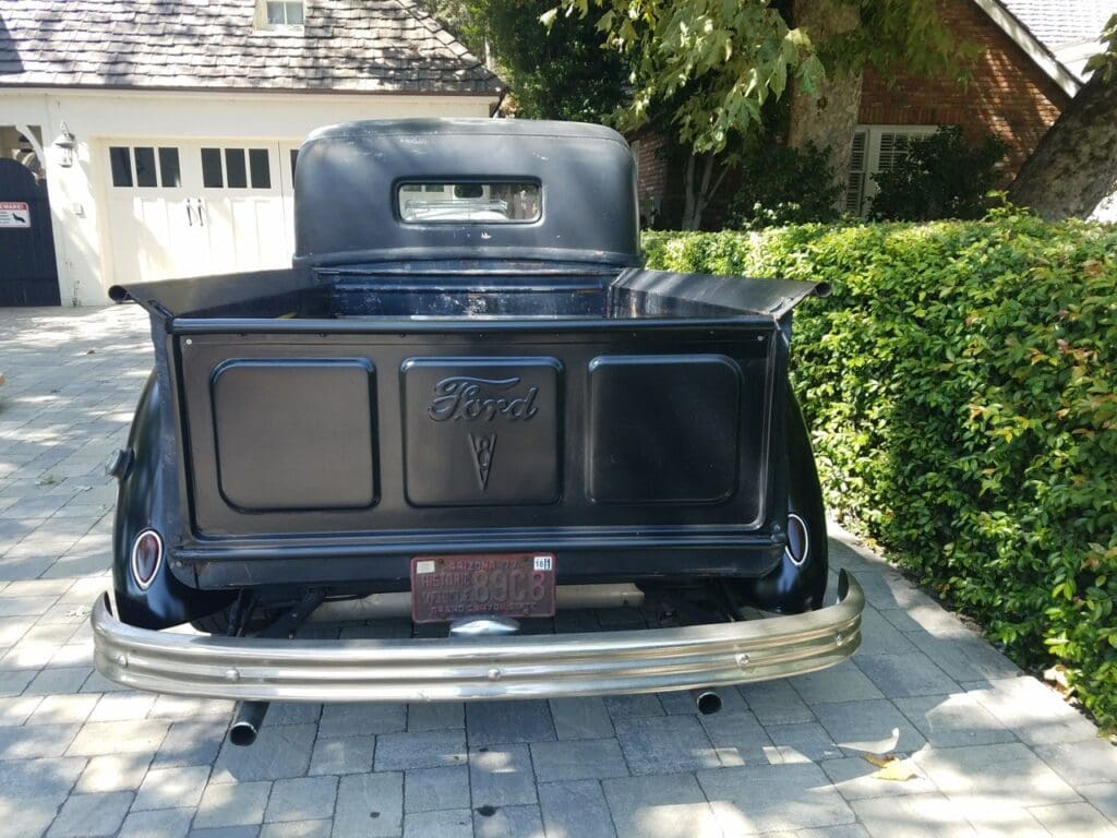 Rear view of a classic black Ford car with vintage design details.