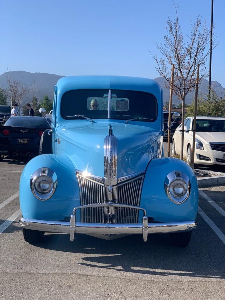 Front view of a vintage blue car parked outdoors.