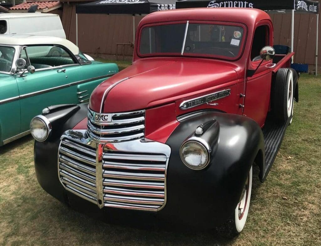 Classic red and black vintage pickup truck with shiny chrome grille.