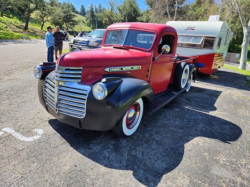 Vintage red and black pickup truck at an outdoor event.