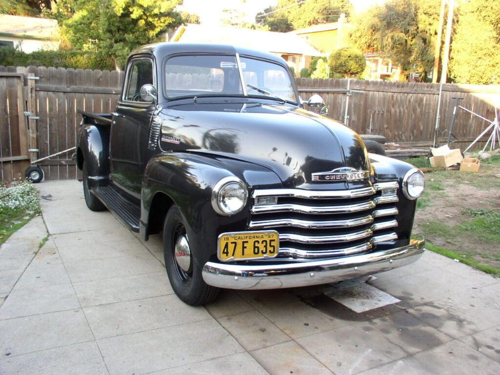 Classic black vintage pickup truck parked outdoors on driveway.