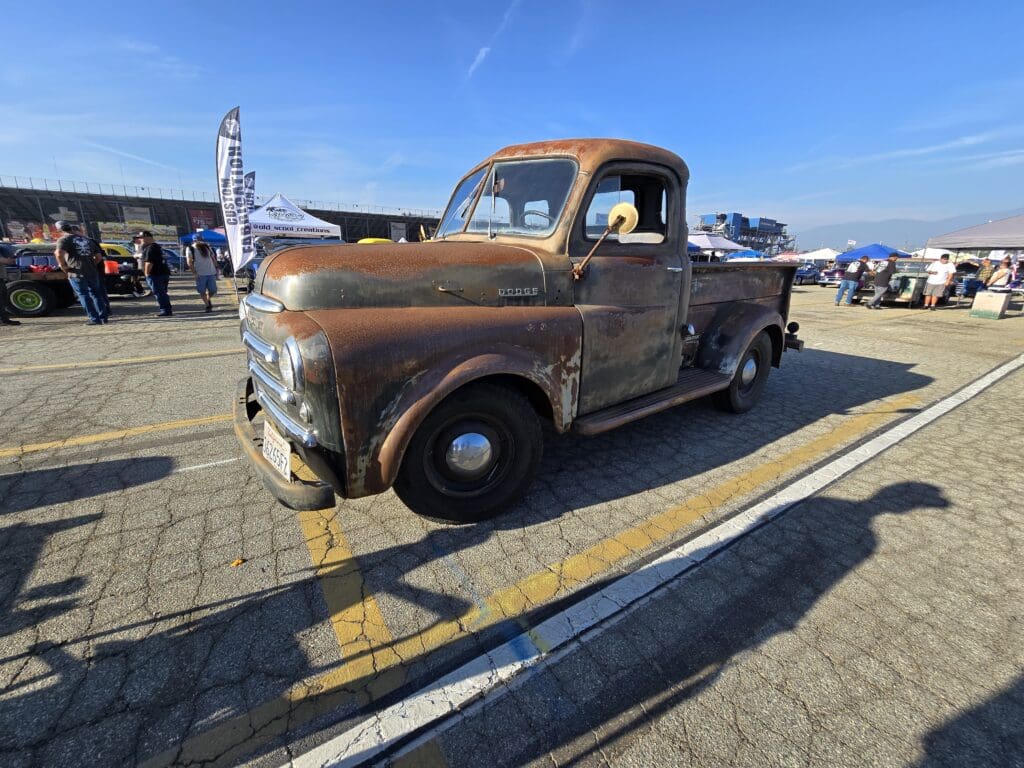 Rusty vintage pickup truck parked outdoors under clear blue sky.