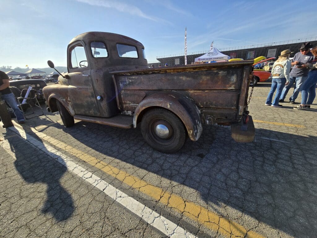 Rusty vintage pickup truck parked outdoors under clear blue sky.