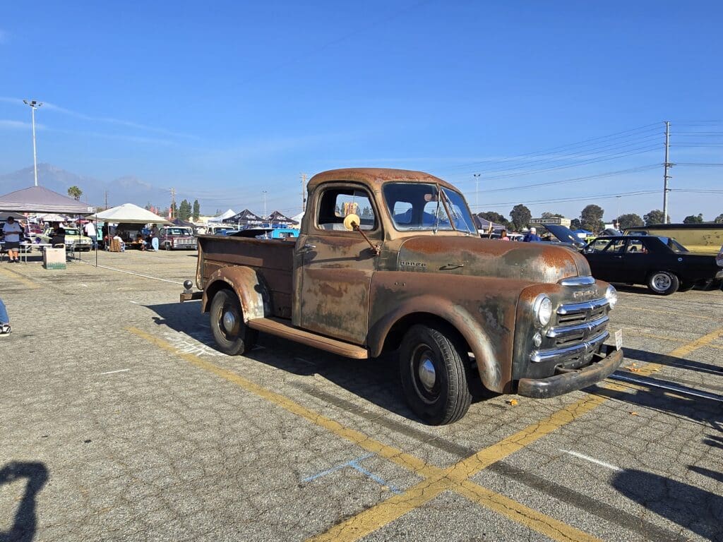 Rusty vintage pickup truck parked outdoors under a clear sky.
