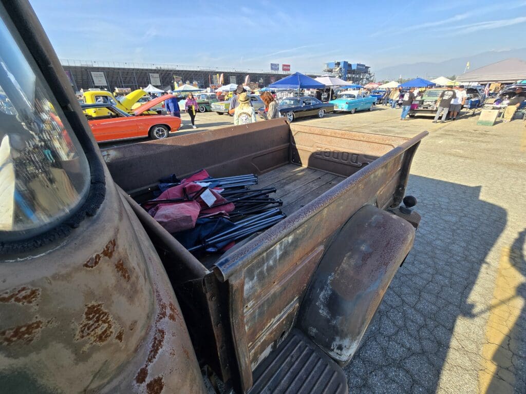 Vintage car with tools and parts in the bed at a classic car event.