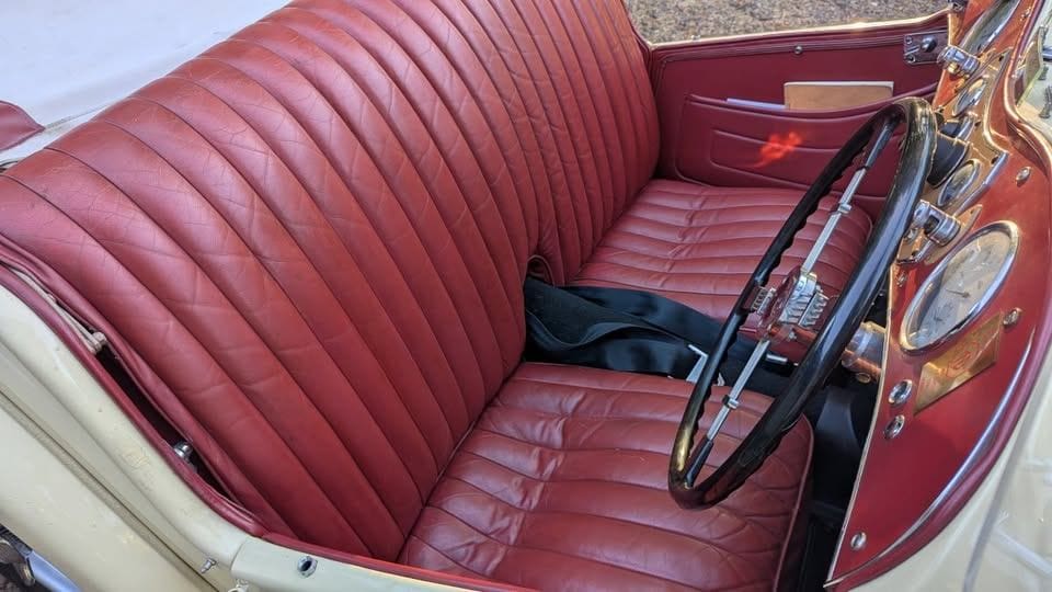 Interior of a vintage red car with leather seats and classic steering wheel.
