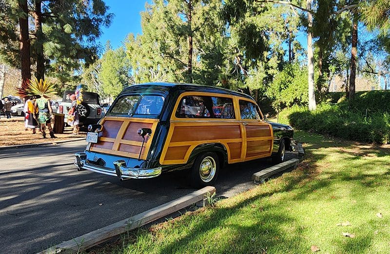 Classic wooden panel station wagon parked outdoors on a sunny day.