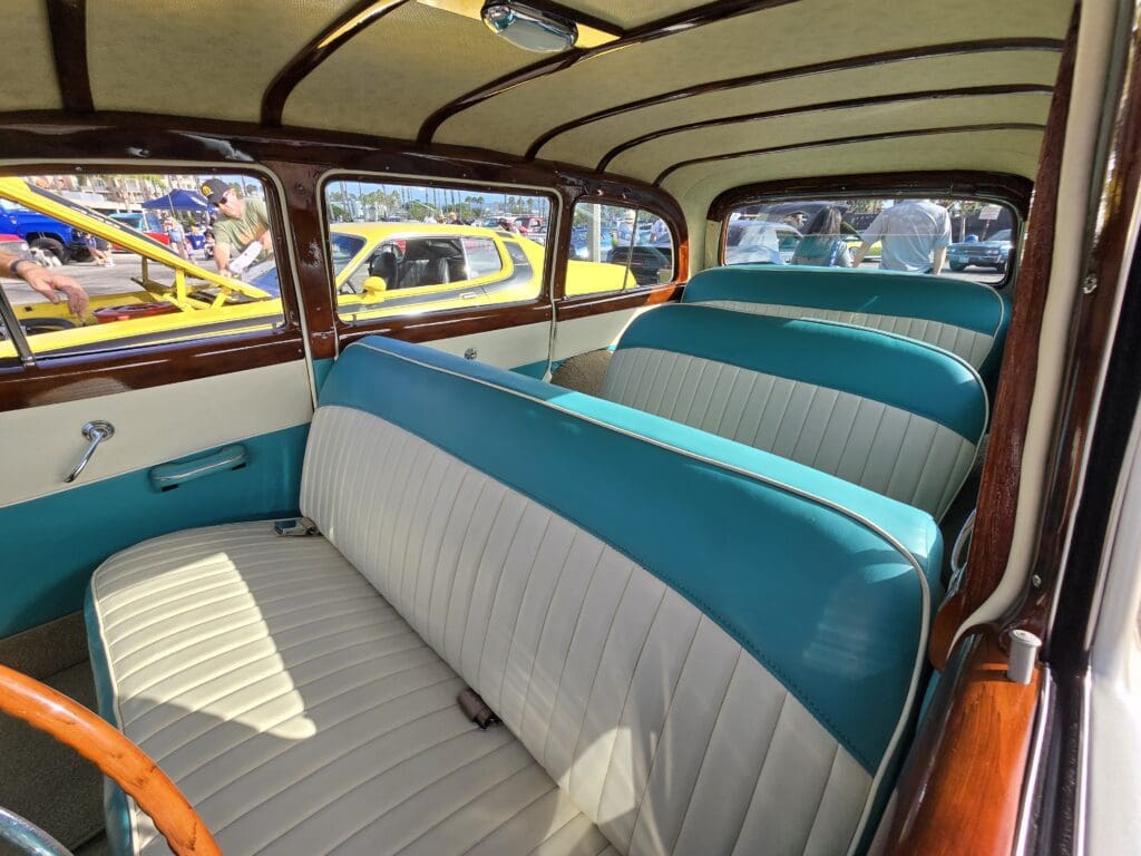 Interior view of a vintage car with turquoise and gray seats.