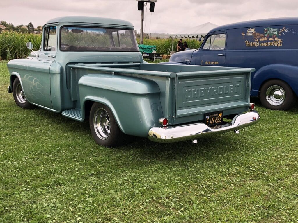 Classic vintage pickup truck parked on grass with a weathered paint job.
