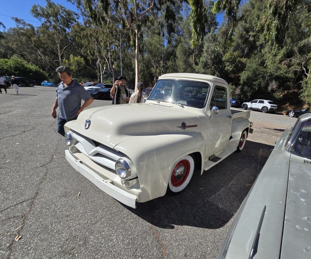 Classic white vintage pickup truck parked outdoors with a person nearby.