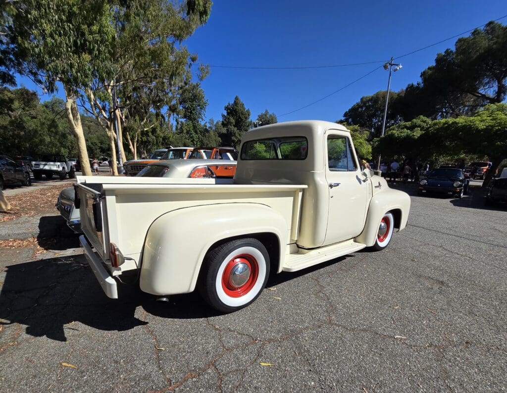 Classic cream-colored vintage pickup truck with red and white wheels.
