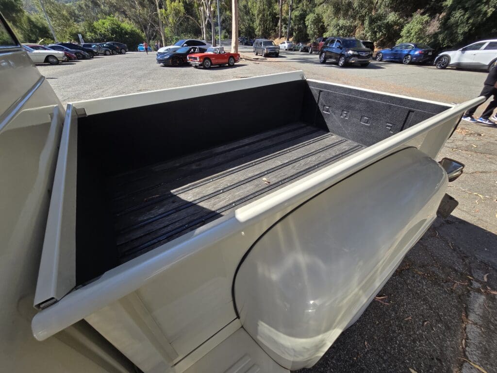 Empty truck bed with a black liner in a parking lot.