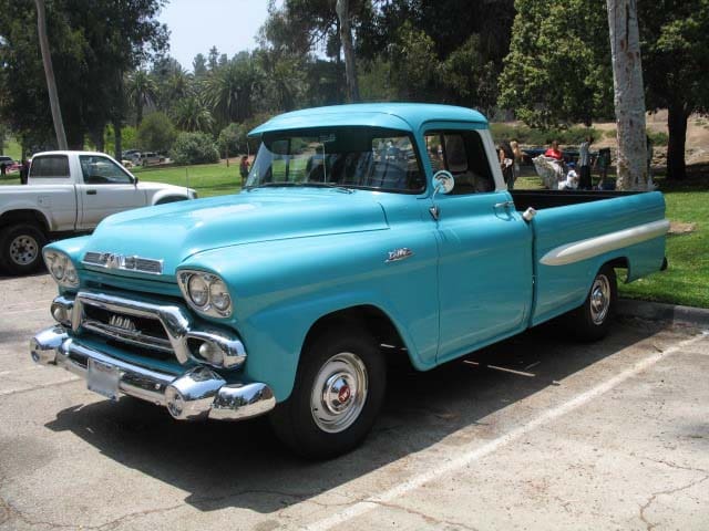 A classic turquoise vintage pickup truck parked outdoors.