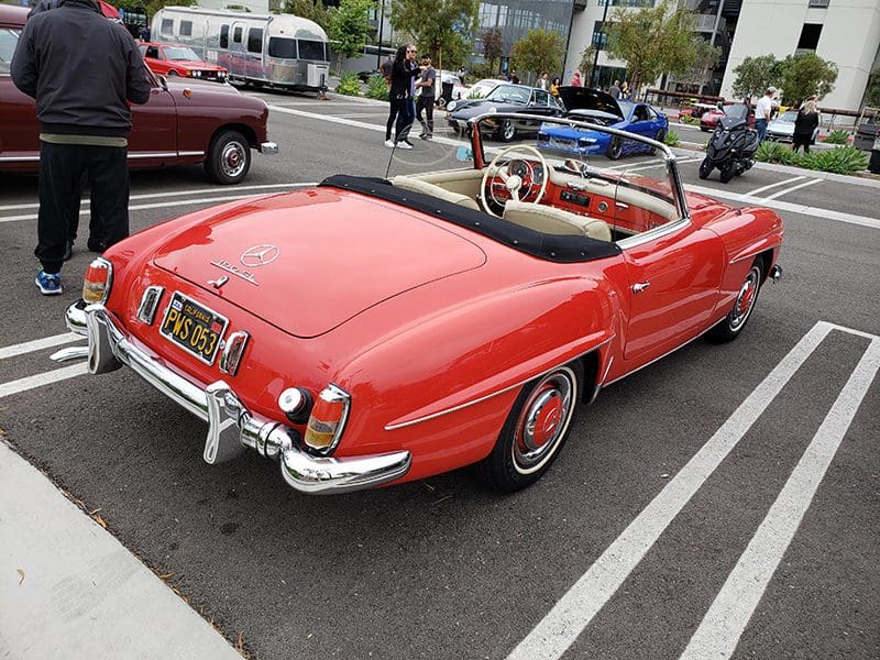 Red vintage convertible car parked in a lot.