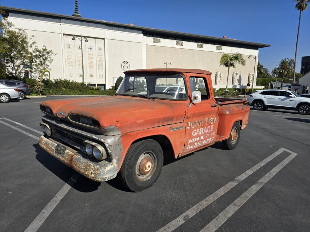 Rusty vintage pickup truck parked outdoors under clear sky.